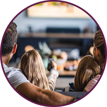 Back view of a relaxed family watching TV on sofa in the living room 