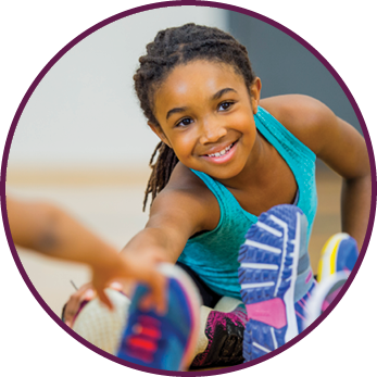 A young African American girl leads a stretch during gym class as part of their yoga routine 